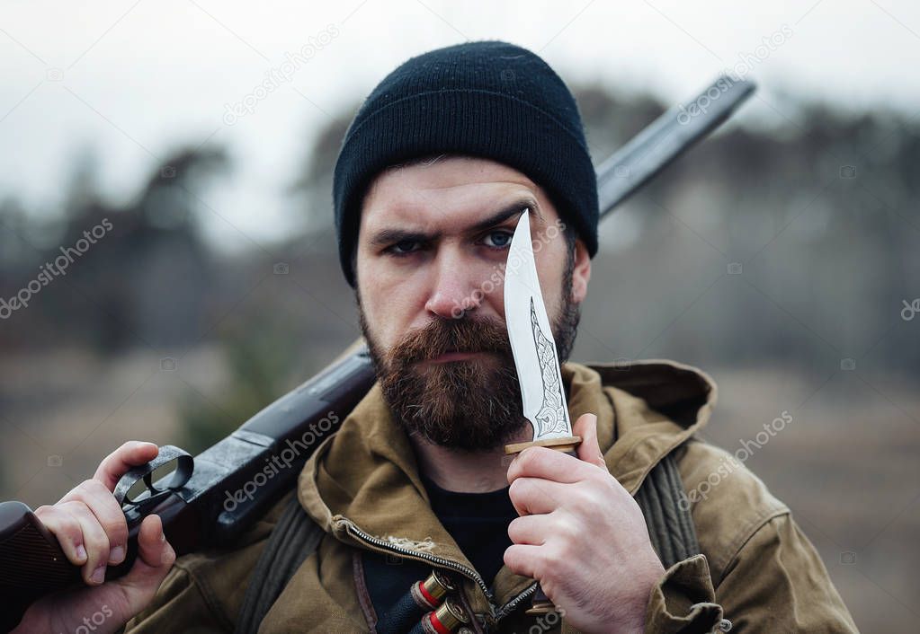 Bearded hunter with professional equipment walking in the woods