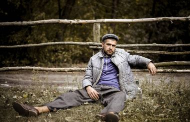 Eski giysiler içinde neşeli bir köylü bir kulübede çalışır olduğu yerde bir sürü saman