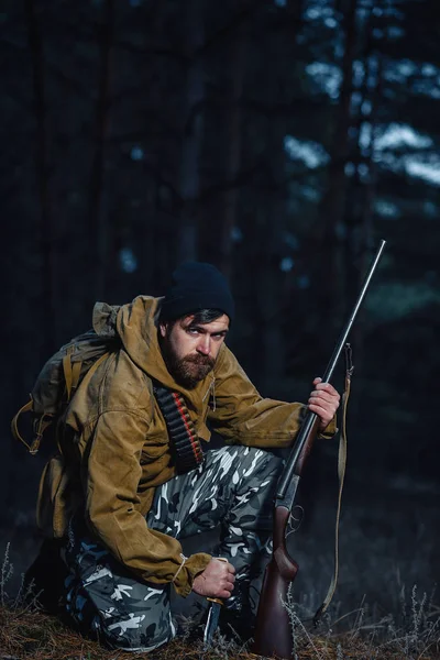 Cazador barbudo con equipo profesional caminando por el bosque — Foto de Stock