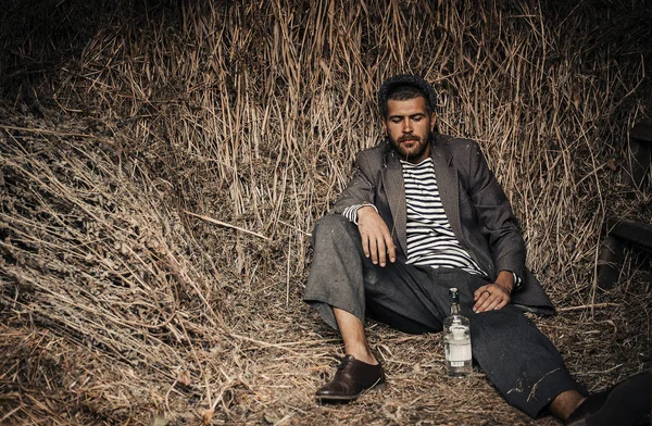 Eski kıyafetleri alkol onun elinde bir şişe ile neşeli bir köylü bir kulübe bir kuru ot bırakır