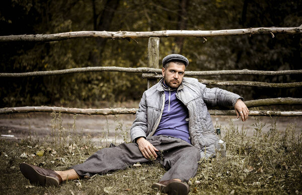 A cheerful peasant in old clothes works in a shed where there is a lot of hay