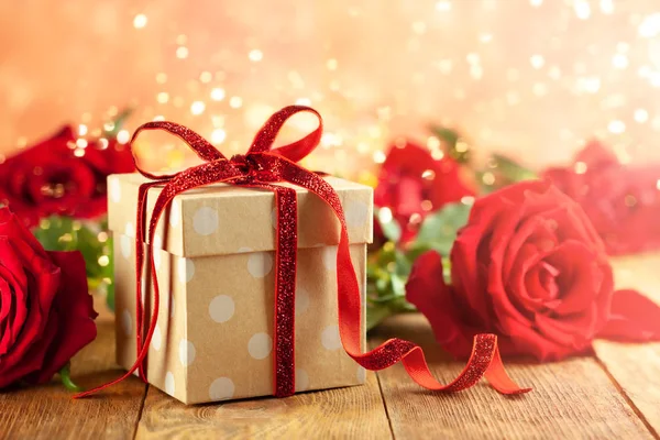 Κουτί δώρου με κόκκινη κορδέλα φιόγκο και κόκκινα τριαντάφυλλα. — Φωτογραφία Αρχείου