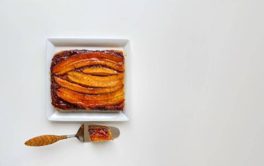 Beyaz masadaki lezzetli baş aşağı karamelli muzlu kek. Ev yapımı fırın kavramı, kopyalama alanı olan düz konum