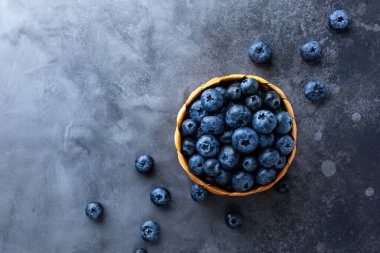 Mini sepetteki taze organik yaban mersini ve klasik karanlık masa. Sağlıklı beslenme kavramı. Üst görünüm, alanı kopyala.