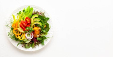 Lezzetli sağlıklı avokado salatası, domates, salatalık, biber, marul, beyaz tabakta mikroçerez. Temiz yemek, yemek kasesi. Üst görünüm.