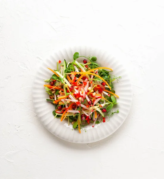 新鮮なニンジンのおいしい健康的なサラダ キュウリ タマネギ レタス 白いプレート上の松の実とザクロ きれいな食事だ トップ表示 — ストック写真