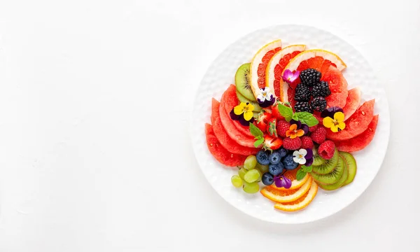 新鮮な果物 白いプレート上の食用花のおいしい健康的なサラダ きれいな食事だ トップ表示 — ストック写真