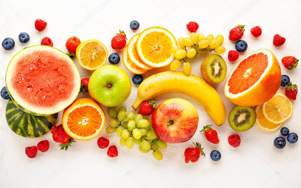 Assorted fresh fruits and berries on white background. Clean eating, healthy life. Top view.
