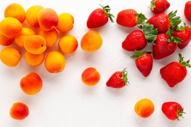 Beyaz arka planda taze organik kayısılar ve çilek. Vejetaryen, temiz ve sağlıklı beslenme konsepti. Düz yat, boşluğu kopyala.