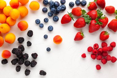Beyaz arka planda taze organik kayısılar, çilek, yabanmersini ve böğürtlen. Vejetaryen, temiz ve sağlıklı beslenme konsepti. Düz yat, boşluğu kopyala.