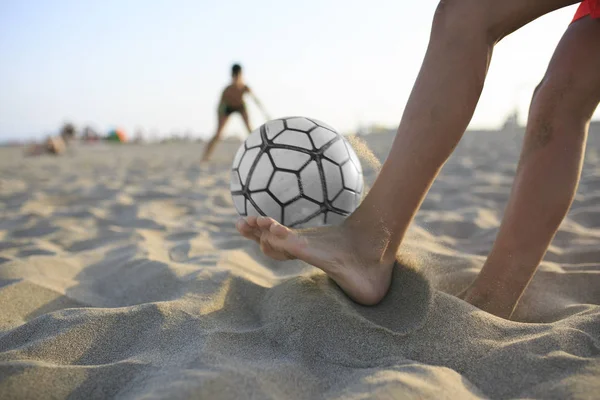 Çocuk sahilde futbol oynuyor. — Stok fotoğraf