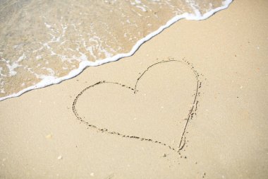 Aşk kalp işareti kum plajı üzerinde çizmek