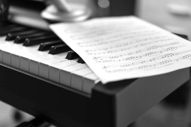 Elektronik piyano ve müzik sayfası. Siyah beyaz fotoğraf, müzikal arkaplan