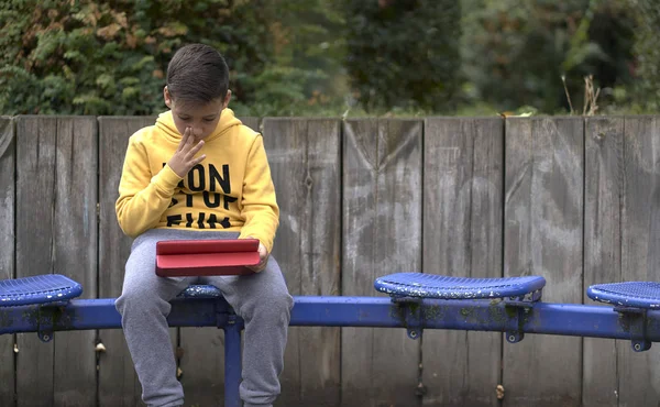 Jongen met gele sweatshirt surfen met zijn tablet in de straat — Stockfoto