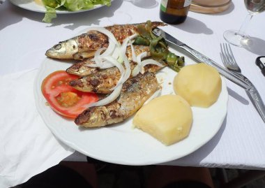 Bir tabak soğanlı ve patatesli sardalya balığı.