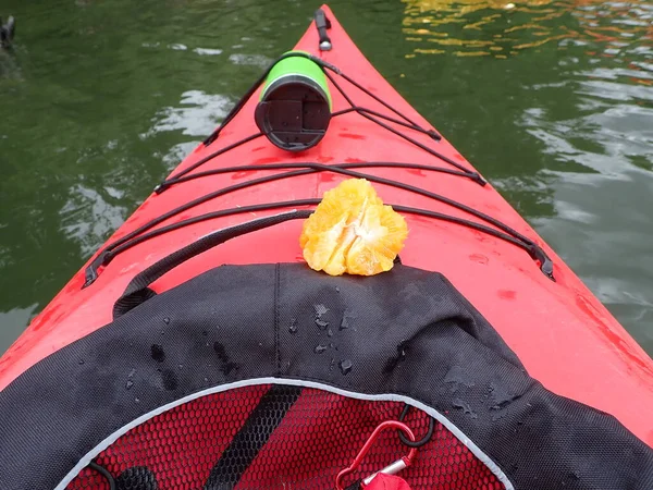 Κόκκινο καγιάκ βάρκα με πορτοκαλί και πράσινο νερό μπουκάλι στο νερό — Φωτογραφία Αρχείου