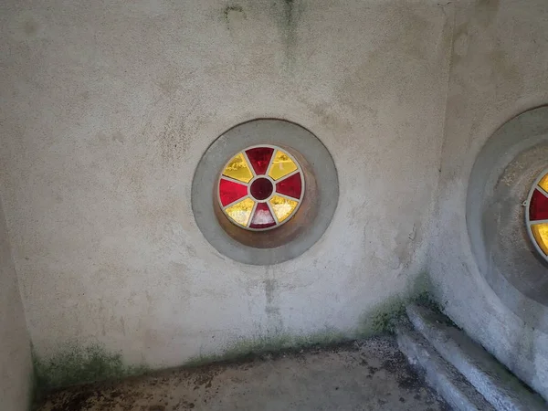 Red and yellow glass in circular window on dirty wall — Stock Photo, Image