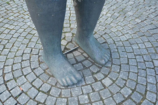 Grandes pés cinzentos de estátua com chão de paralelepípedos — Fotografia de Stock