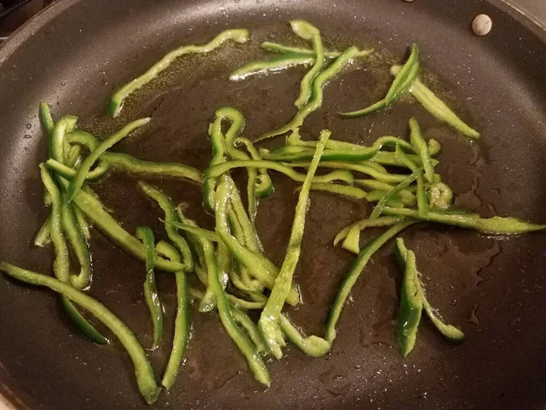 Pimentas verdes fatiadas com óleo na frigideira no fogão — Fotografia de Stock