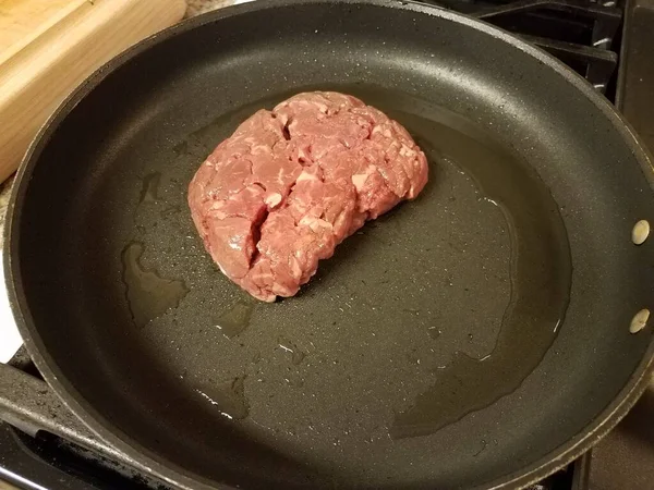 Carne crua de bife com óleo na frigideira no fogão — Fotografia de Stock