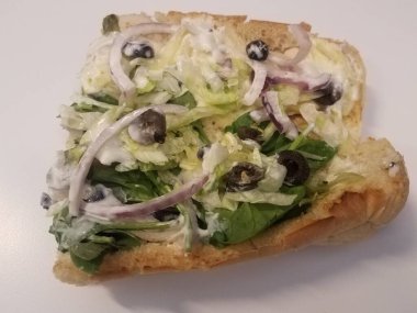submarine sandwich with onion, mayonnaise, lettuce, and olives