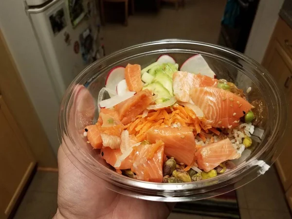 Hand holding plastic container of raw salmon and avocado and rice — Stock Photo, Image