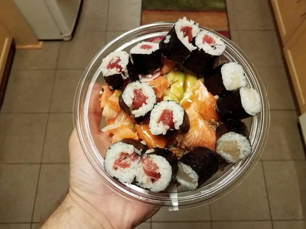 Πλαστικό δοχείο χειρός με ωμό σολομό και ρολά σούσι — Φωτογραφία Αρχείου