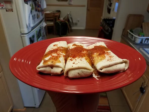 Burritos em chapa vermelha com salsa picante e pimenta em pó — Fotografia de Stock