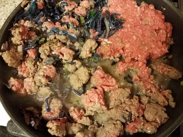 raw ground turkey and cabbage in frying pan or skillet