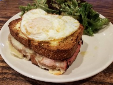 Jambonlu, peynirli ve tabakta salatalı sandviç.