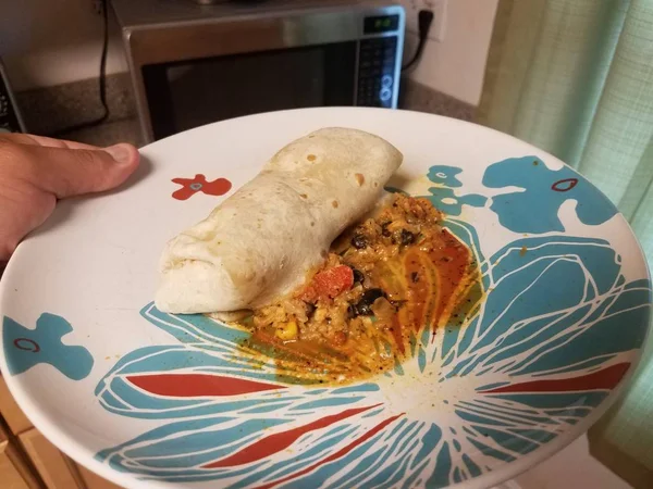Exploded burrito with rice and beans and cheese on plate with microwave — Stock Photo, Image