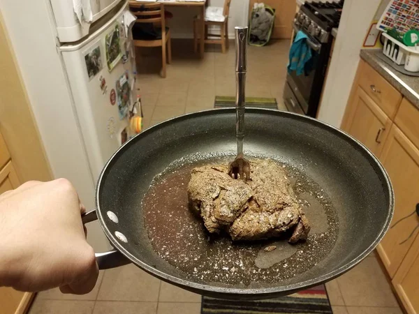 Hand houden koekenpan met rundvlees en sappen en vork — Stockfoto