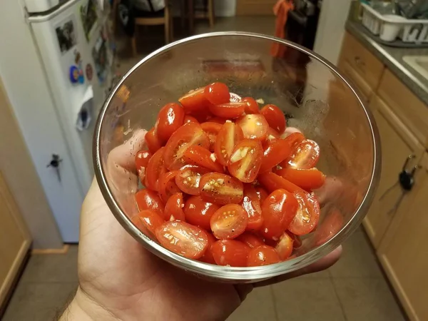 Trzymanie za rękę krojonych czerwonych pomidorów w szklanym pojemniku w kuchni — Zdjęcie stockowe