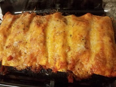 Fırındaki cam kabın içinde peynirli ve soslu tortilla.