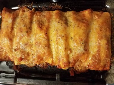 Fırındaki cam kabın içinde peynirli ve soslu tortilla.