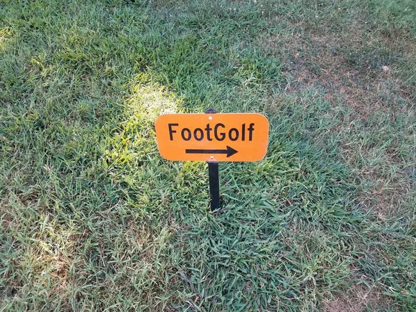 Oranje voet golfbord met zwarte pijl in gras — Stockfoto