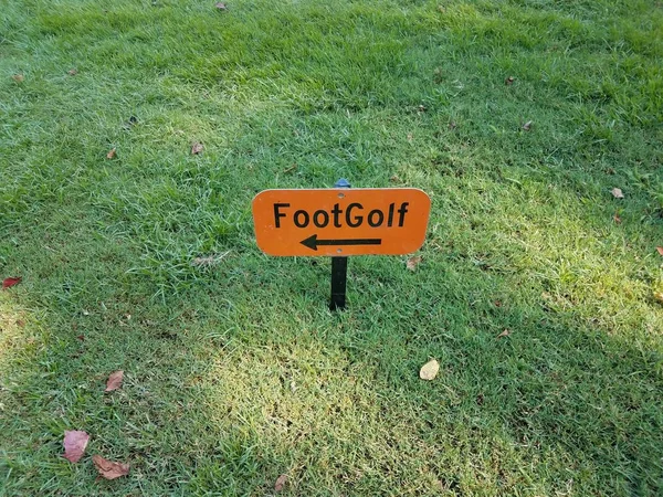 Oranje voet golfbord met zwarte pijl in gras — Stockfoto