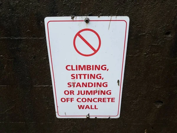 No climbing sitting standing or jumping off concrete wall sign — Stock Photo, Image