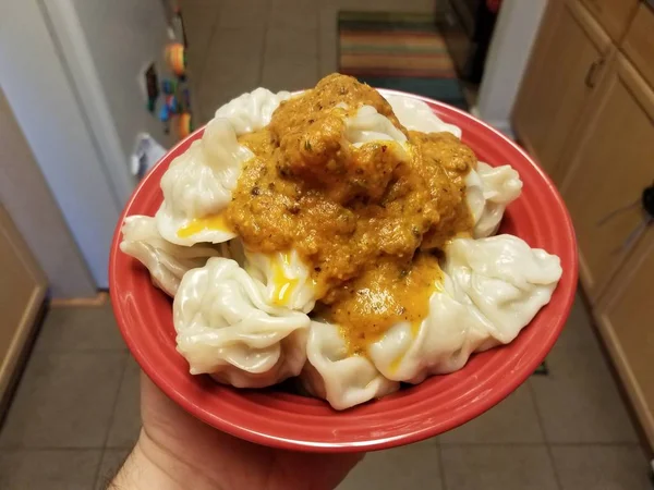 Knoedels en pittige saus in rode kom in keuken — Stockfoto