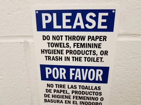 Не бросать бумажные полотенца в туалетную табличку на английском и испанском языках на стену ванной комнаты — стоковое фото