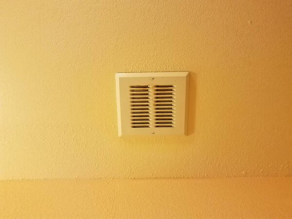 вентиляция в ванной комнате из грязного металла на оранжевом или желтом потолке
