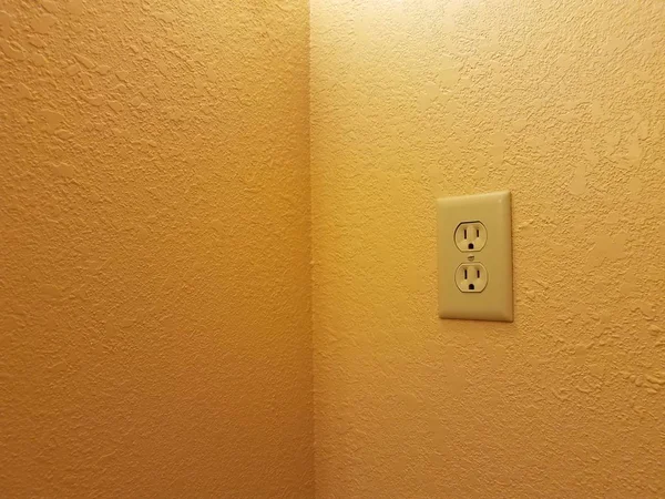 Electrical outlet on orange or yellow painted wall — Stock Photo, Image