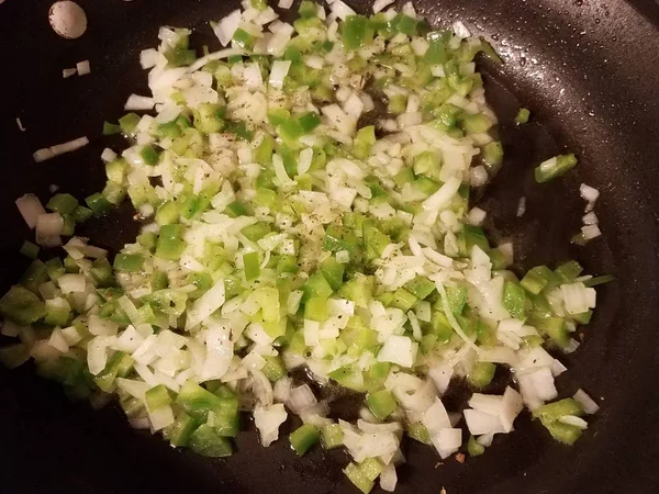 Лук и зеленый перец в масле на сковороде — стоковое фото