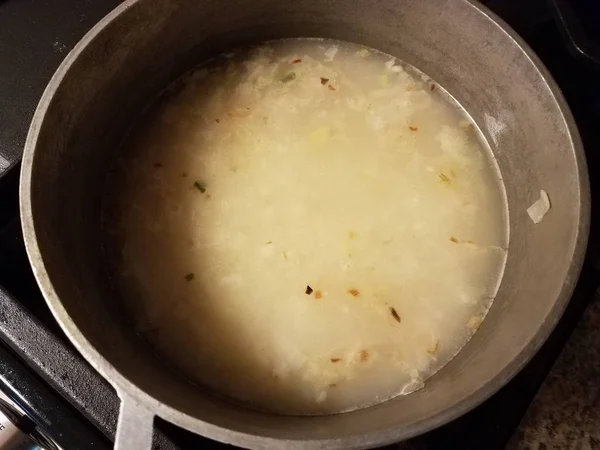 Bouillon avec oignon dans une casserole en métal sur le poêle — Photo