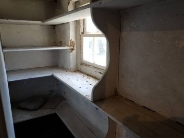 Penceresi ve kirli rafları olan depo odası