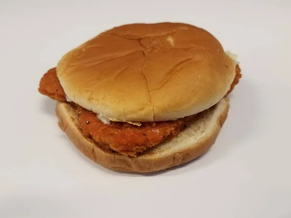 Spicy chicken sandwich and bun on white surface — Stock Photo, Image