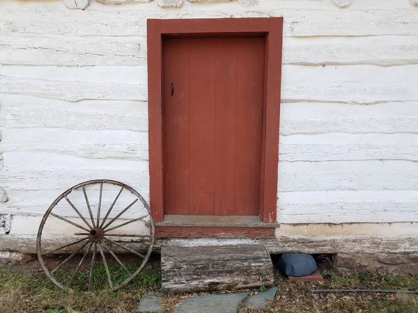 Vecchia ruota di legno e porta rossa e casa bianca — Foto Stock