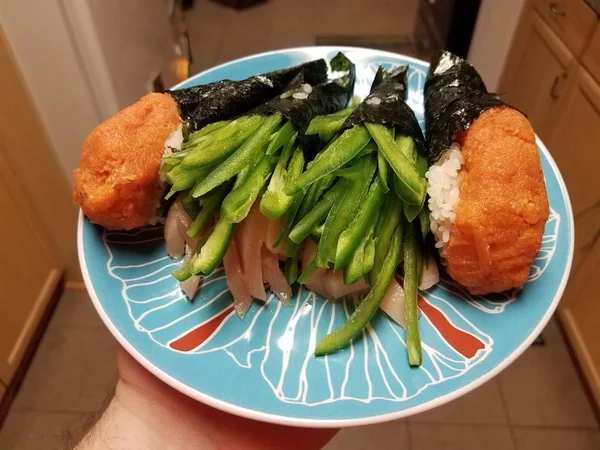 Hand houden sushi broodjes met pittige groene paprika 's en tonijn — Stockfoto