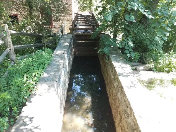 Acqua o ruscello in canale con sassi e foglie — Foto Stock