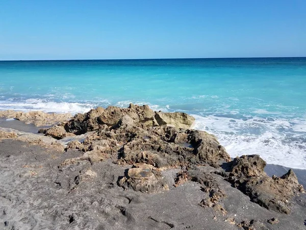 Rocas y arena en la costa en la playa de Florida con el océano y las olas —  Fotos de Stock